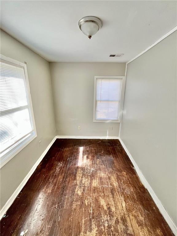 empty room with baseboards, visible vents, and hardwood / wood-style floors