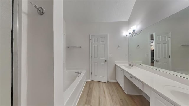 full bath featuring a sink, a textured ceiling, wood finished floors, double vanity, and a bath