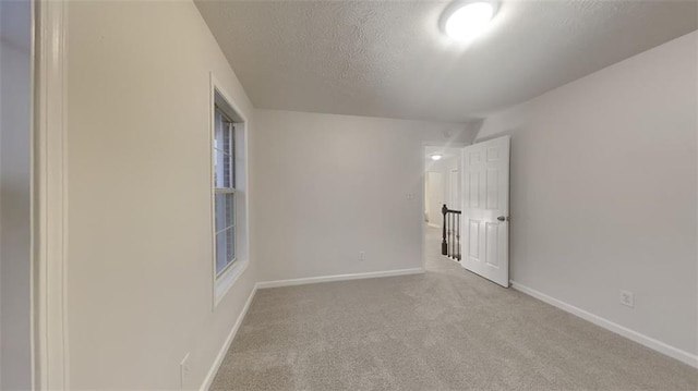 spare room featuring baseboards, carpet floors, and a textured ceiling