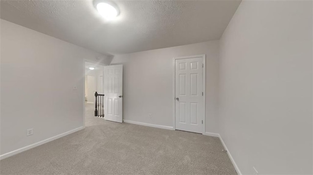 unfurnished bedroom featuring baseboards, a textured ceiling, and carpet flooring