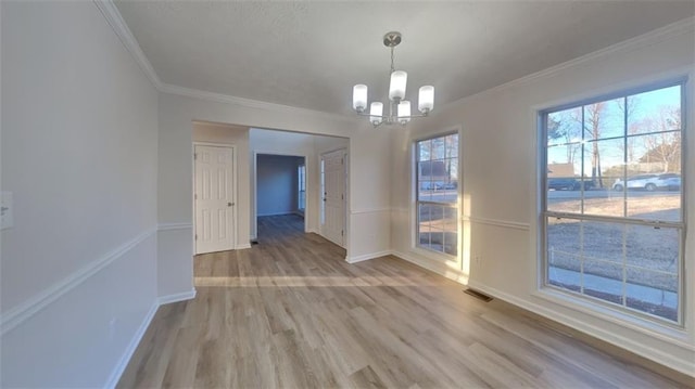 unfurnished dining area featuring visible vents, light wood-style flooring, crown molding, and an inviting chandelier