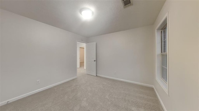 unfurnished room featuring light carpet, visible vents, a textured ceiling, and baseboards