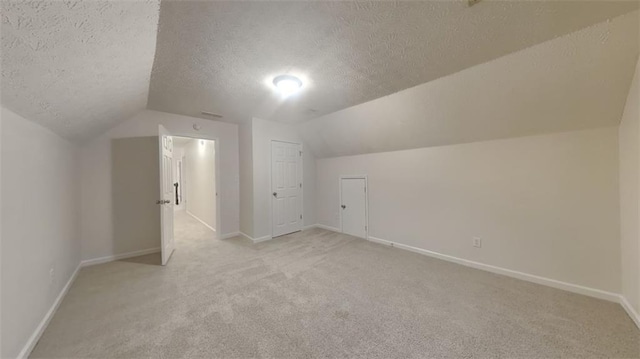 additional living space with light colored carpet, baseboards, a textured ceiling, and vaulted ceiling