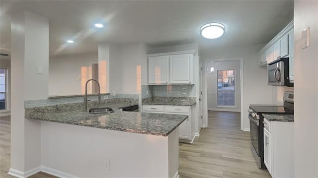 kitchen featuring white cabinetry, dark stone countertops, appliances with stainless steel finishes, and a sink