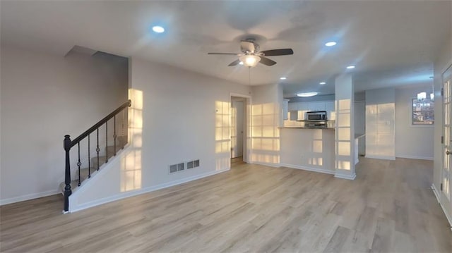 unfurnished living room with a ceiling fan, baseboards, recessed lighting, stairs, and light wood-style floors