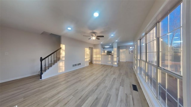 unfurnished living room with light wood finished floors, a healthy amount of sunlight, and baseboards