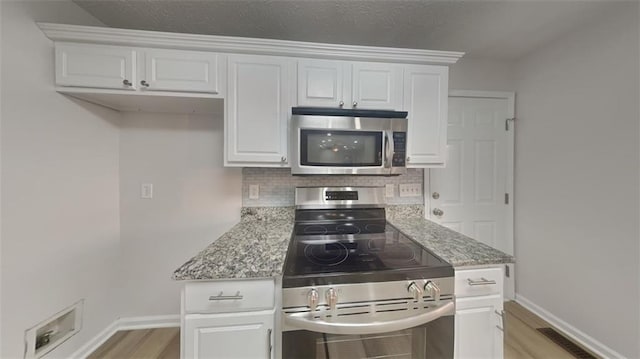 kitchen featuring light stone countertops, backsplash, appliances with stainless steel finishes, and white cabinetry