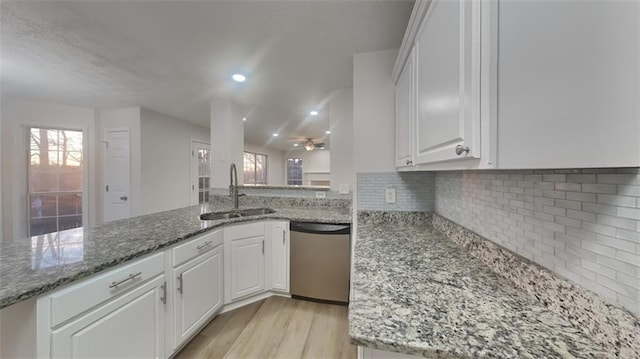 kitchen featuring light stone countertops, light wood finished floors, a sink, white cabinets, and dishwasher