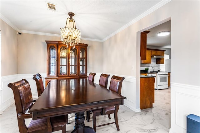 dining space featuring a chandelier, a textured ceiling, and ornamental molding