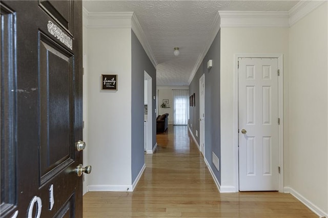 hallway featuring ornamental molding, a textured ceiling, and light hardwood / wood-style flooring