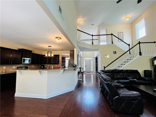 interior space featuring dark wood-style flooring, visible vents, a towering ceiling, baseboards, and stairway