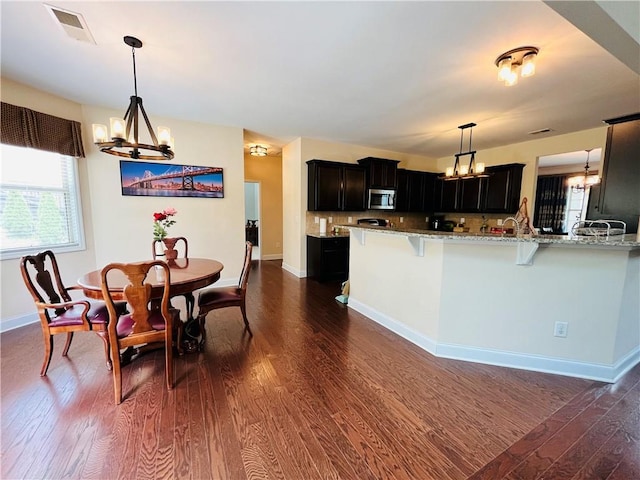 kitchen with a chandelier, stainless steel microwave, dark wood finished floors, and visible vents