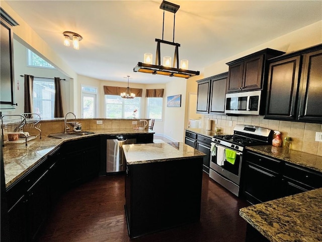 kitchen with stainless steel appliances, a wealth of natural light, tasteful backsplash, a sink, and dark stone countertops