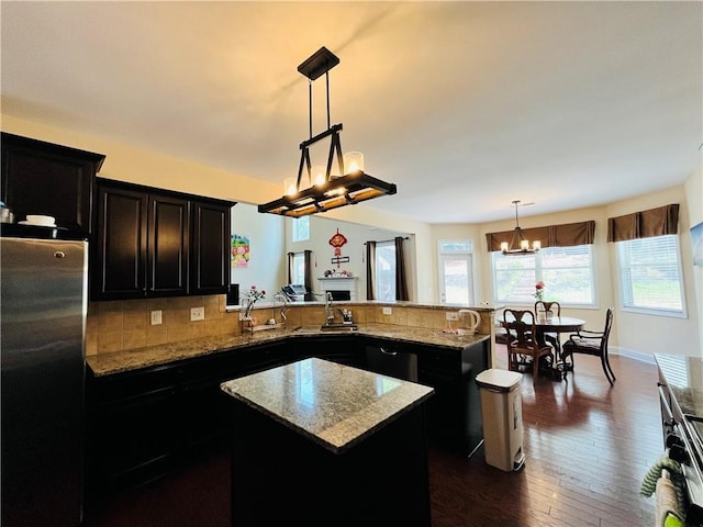 kitchen with appliances with stainless steel finishes, a chandelier, dark cabinetry, and a kitchen island