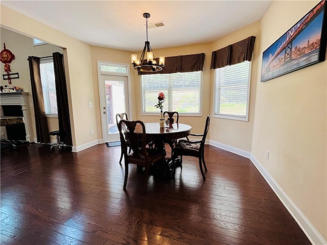 dining area featuring a fireplace, baseboards, dark wood finished floors, and a notable chandelier