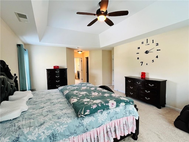 bedroom featuring baseboards, visible vents, a tray ceiling, and light colored carpet