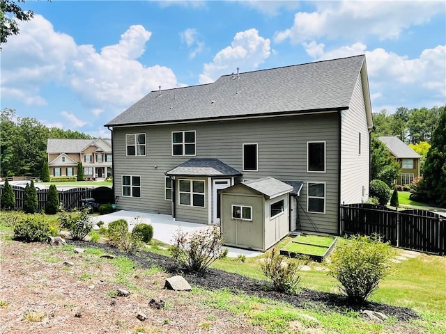 rear view of house featuring a yard, a fenced backyard, a patio, and roof with shingles