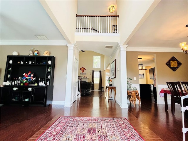 foyer entrance with wood finished floors, decorative columns, and crown molding