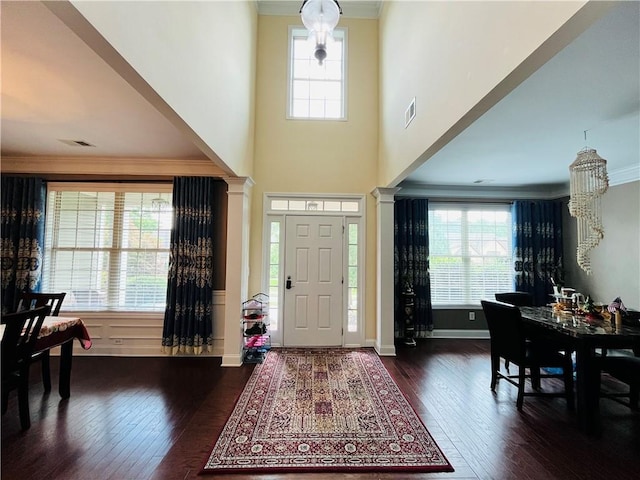 foyer with decorative columns, visible vents, ornamental molding, and hardwood / wood-style floors