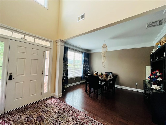 foyer entrance with dark wood-style floors, ornamental molding, decorative columns, and visible vents