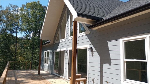 view of side of home featuring a shingled roof and a deck