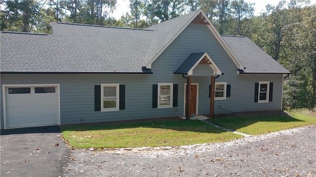 view of front of property featuring a garage, a front lawn, and roof with shingles