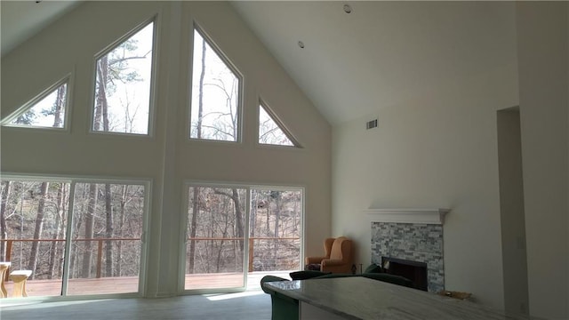 living room featuring high vaulted ceiling, a fireplace, and visible vents