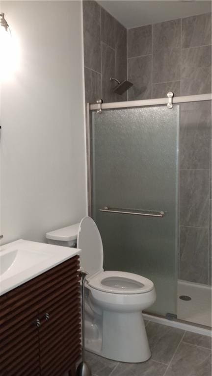 bathroom featuring toilet, a shower stall, vanity, and tile patterned floors