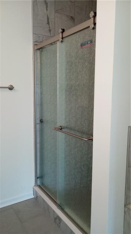 bathroom with a stall shower, tile patterned flooring, and baseboards