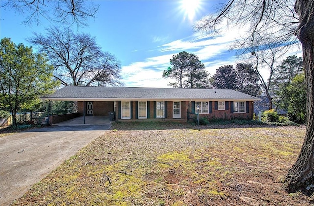 ranch-style house with an attached carport, concrete driveway, and brick siding