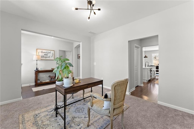 office space with baseboards, dark carpet, and a notable chandelier