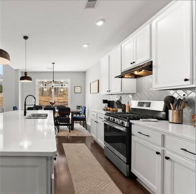 kitchen featuring under cabinet range hood, a sink, light countertops, stainless steel gas stove, and a center island with sink