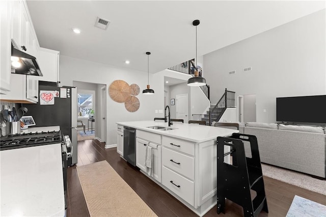 kitchen with light countertops, a sink, a kitchen island with sink, and white cabinetry