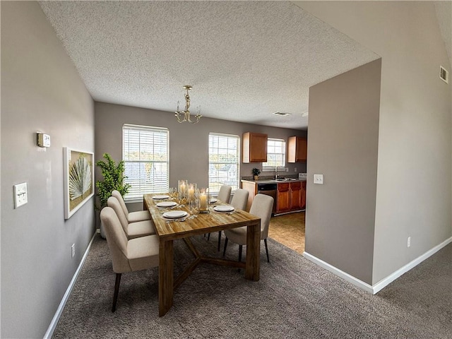 carpeted dining space with a chandelier, sink, and a textured ceiling