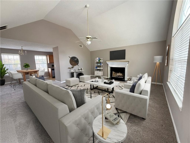 carpeted living room featuring ceiling fan with notable chandelier and vaulted ceiling