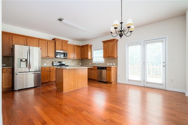 558 Olympic Way, Acworth, GA 30102 - kitchen featuring appliances with stainless steel finishes, a chandelier, brown cabinets, and decorative backsplash