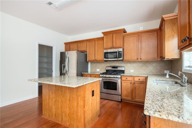 558 Olympic Way, Acworth, GA 30102 - kitchen with appliances with stainless steel finishes, dark wood-type flooring, brown cabinetry, tasteful backsplash, and a center island