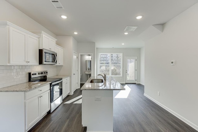 kitchen featuring white cabinetry, stainless steel appliances, an island with sink, sink, and light stone counters