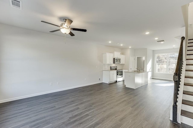 unfurnished living room with dark wood-type flooring, ceiling fan, and sink