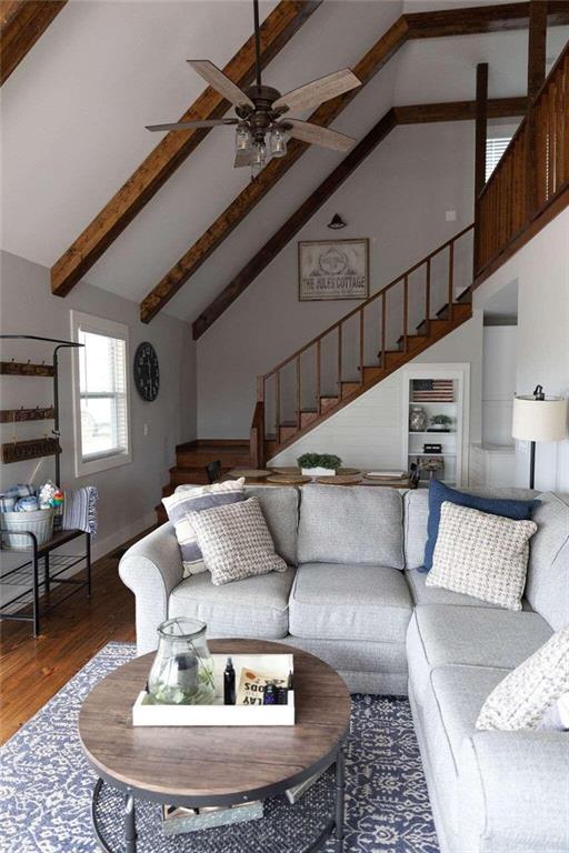 living room with hardwood / wood-style flooring, ceiling fan, beam ceiling, and high vaulted ceiling