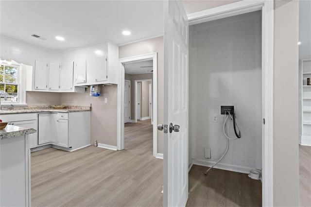 kitchen with light stone countertops, light hardwood / wood-style flooring, and white cabinets