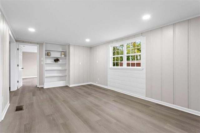 empty room featuring hardwood / wood-style floors and built in shelves