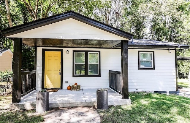 rear view of property featuring a yard and a porch