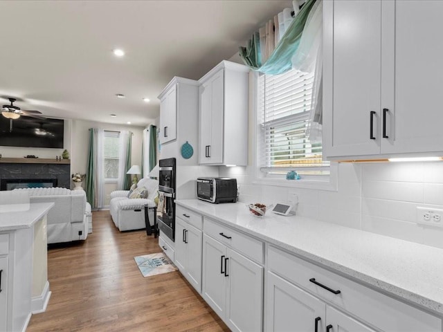 kitchen with light wood finished floors, white cabinetry, open floor plan, and decorative backsplash