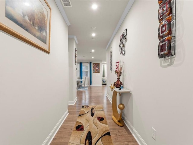 corridor with baseboards, ornamental molding, wood finished floors, and recessed lighting