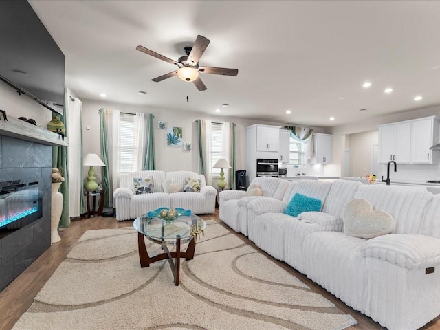 living room featuring recessed lighting, ceiling fan, a tiled fireplace, and wood finished floors