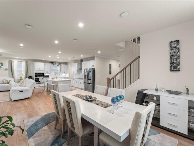 dining room featuring light wood-style floors, recessed lighting, and stairs