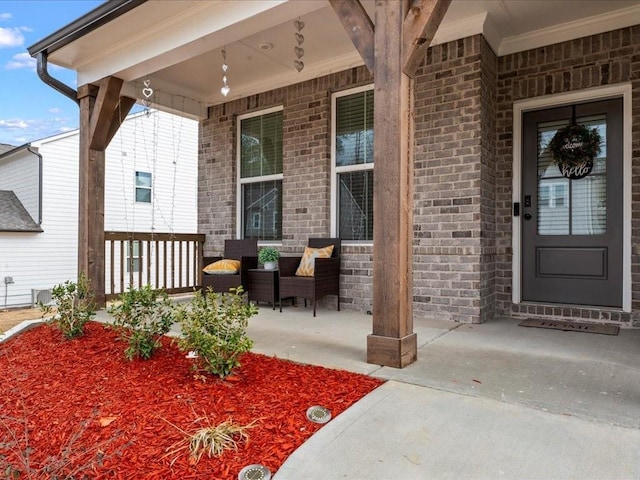 entrance to property featuring covered porch and brick siding