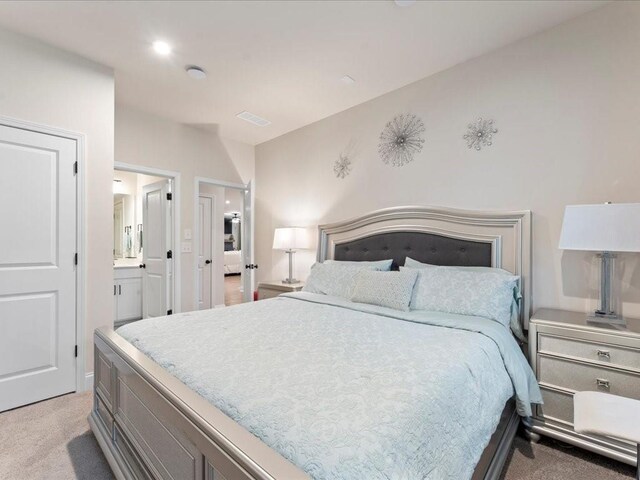 bedroom featuring light carpet, ensuite bath, and visible vents