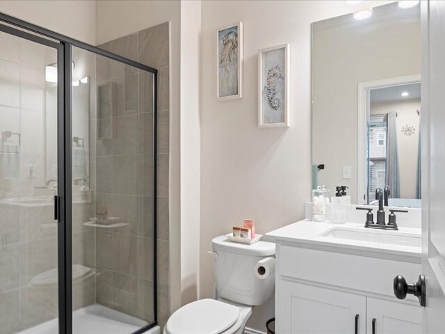 bathroom featuring a shower stall, toilet, and vanity